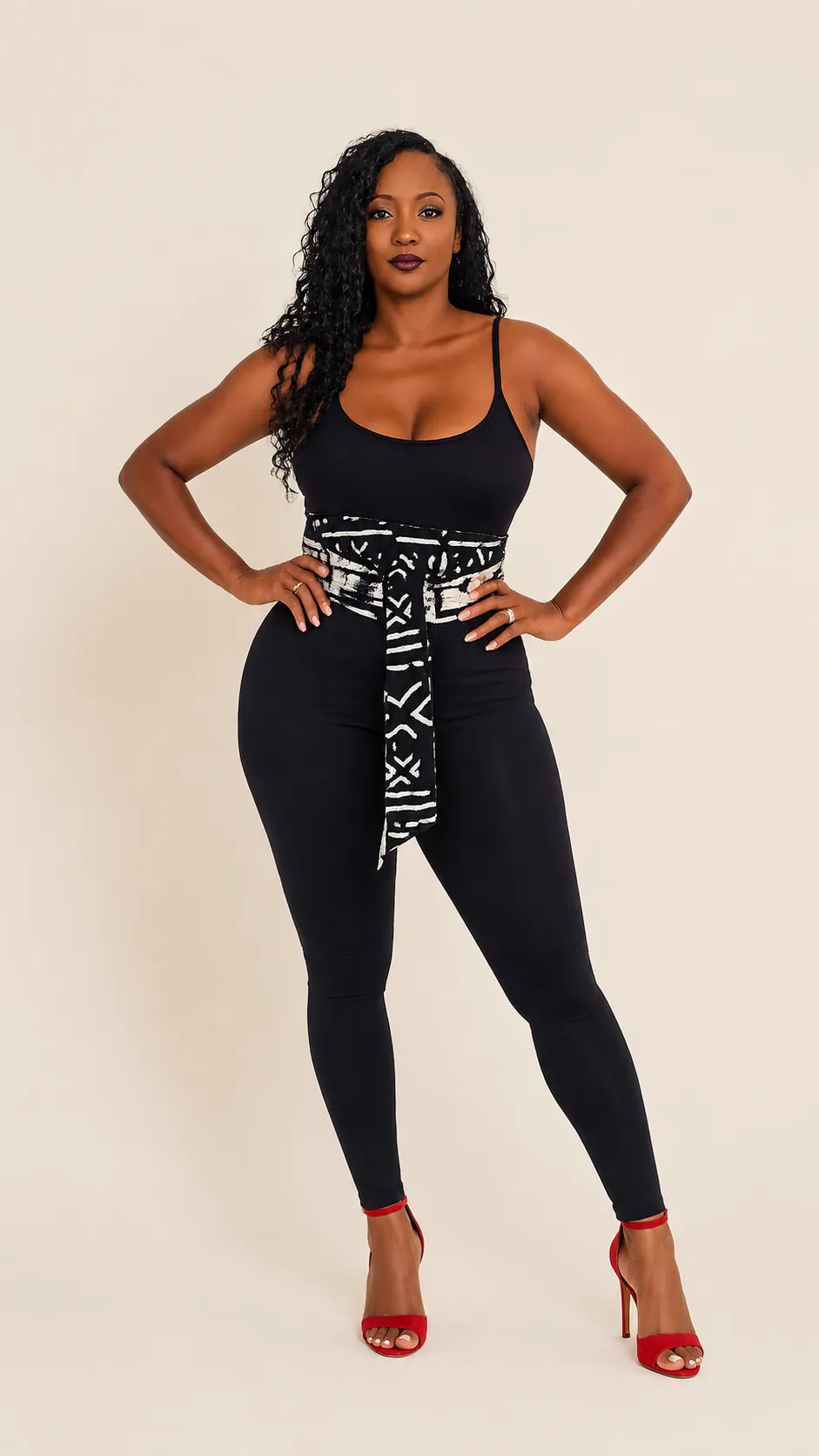 Black and white mudcloth print sash belt cinching a black bodysuit and leggings with red heels