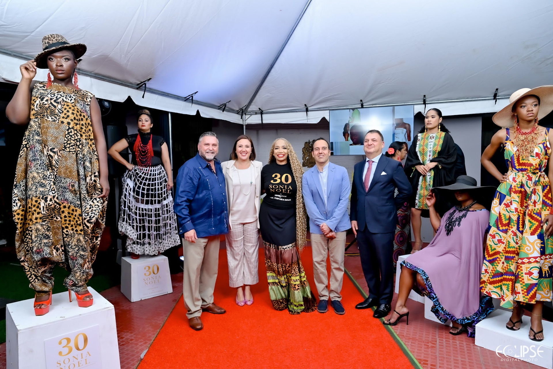 Sonia Noel and diplomatic guests posing with models showcasing 30-year collection pieces