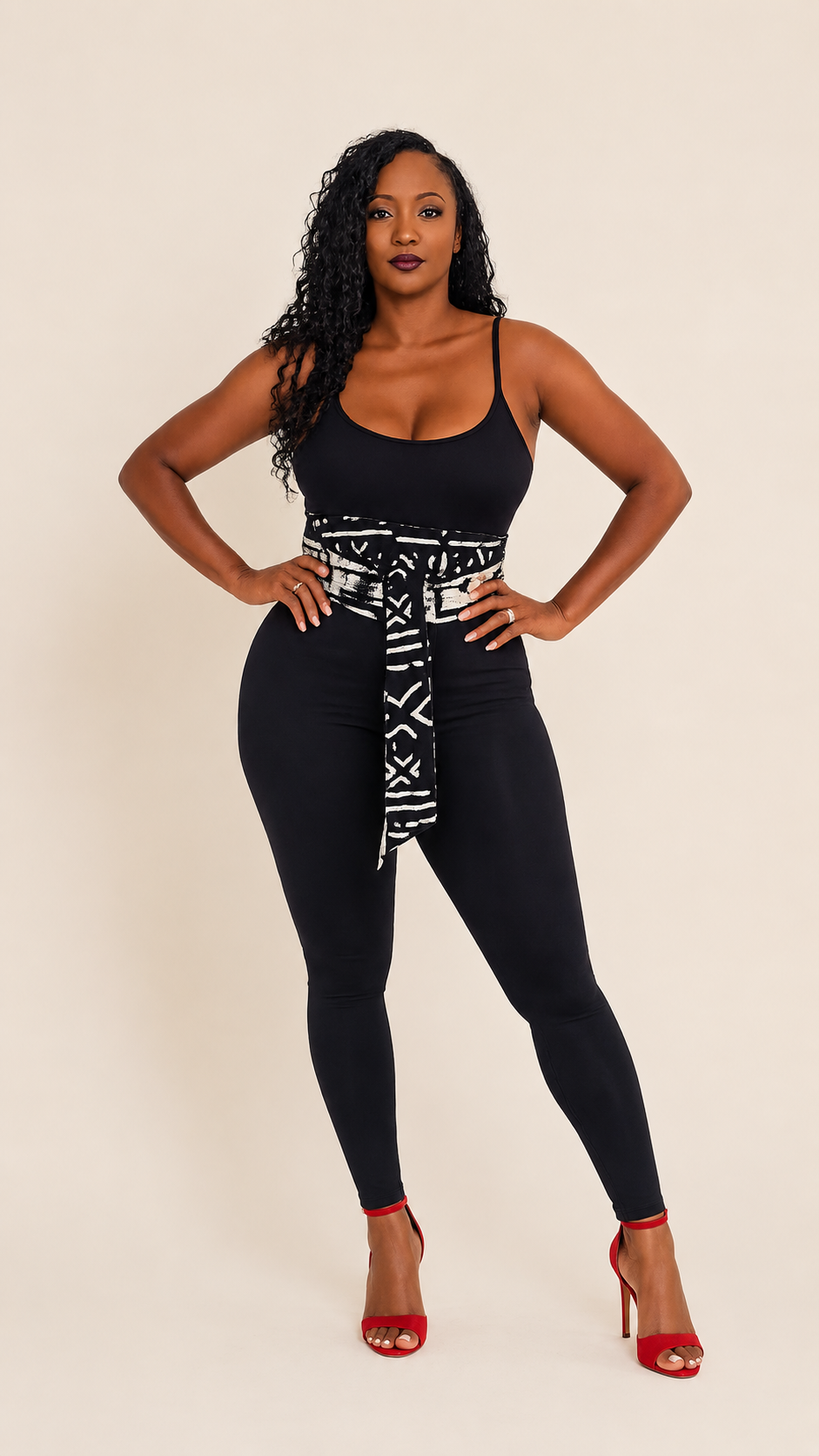 Black and white mudcloth print sash belt cinching a black bodysuit and leggings with red heels
